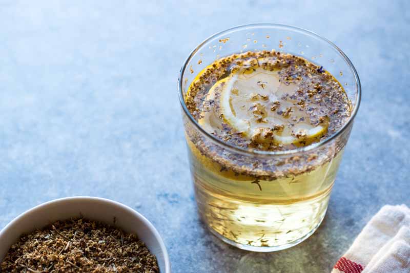 یک لیوان پر از گل سنجد مایع و خشک برای تهیه شربت.